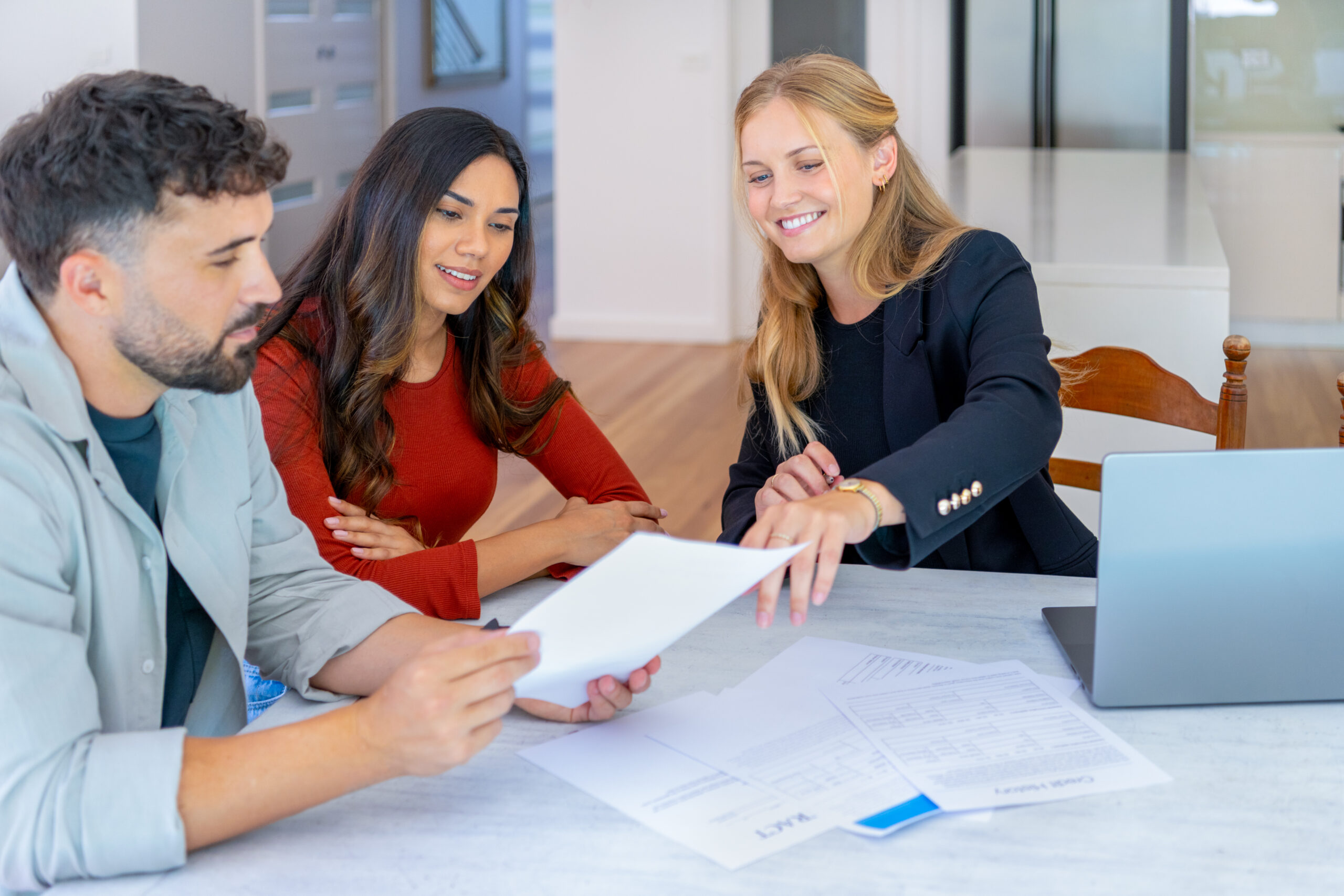 Real Estate or Insurance agent with couple looking through documents.